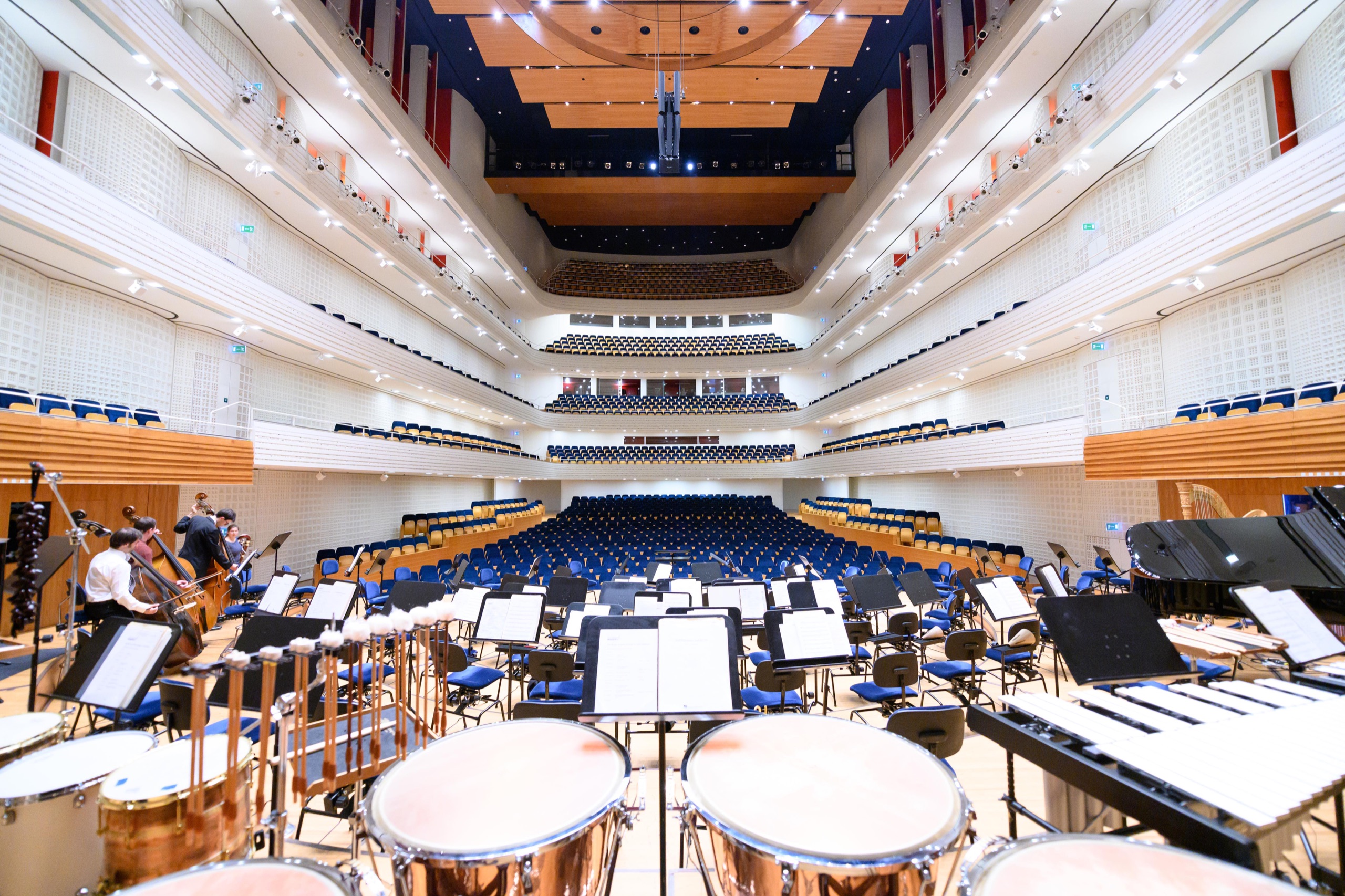 Die leere Bühne des KKL Luzern vor dem Konzert, Blick über Pauken und Notenpulte in den Saal